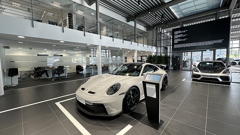 Innenansicht mit mehreren ausgestellten Fahrzeugen des Porsche Zentrum Allgäu in Kempten.